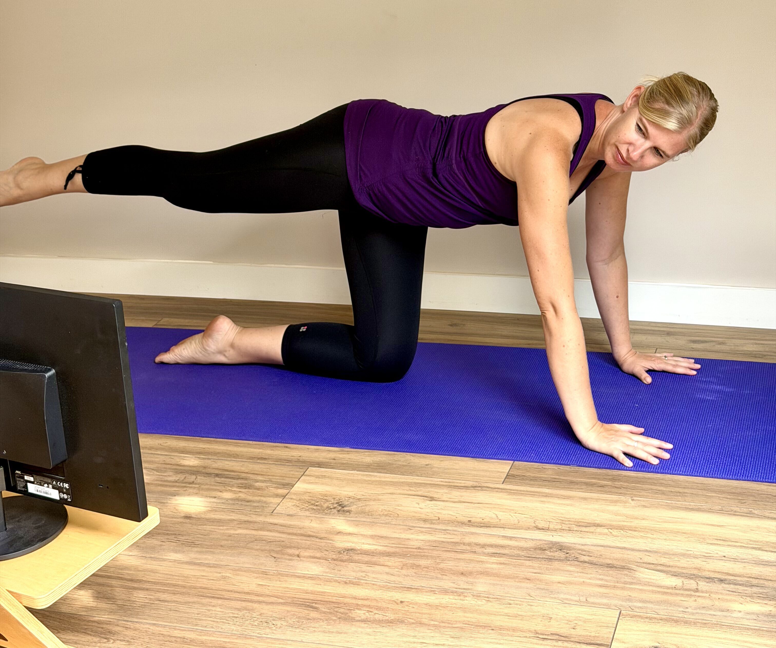 Love Your Spine opposite arm and leg Christine demonstrating an opposite arm and leg exercise on a yoga mat